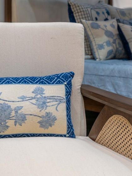 A detail shot showing the fine craftsmanship of our seating. The combination of a solid wood frame, natural cane, and handwoven khadi fabric with delicate embroidery highlights our commitment to texture, detail, and artisanal quality.