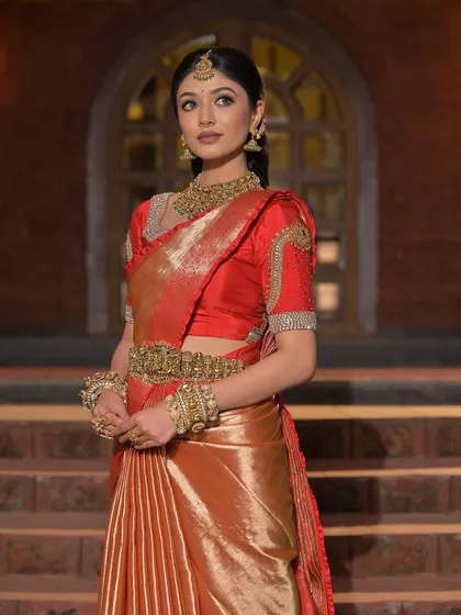 A classic pose showcasing the elegance of the red and gold Kanjeevaram saree.