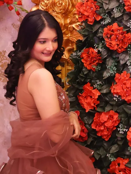 A dreamy party look against a floral backdrop. The soft curls and glowing makeup complement her ruffled lehenga.