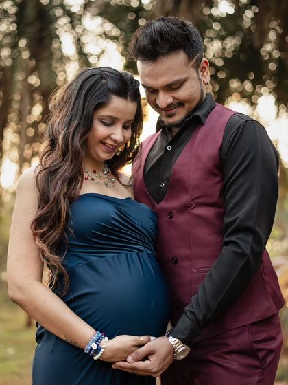 A quiet moment together during their outdoor session. The deep blue of her gown stands out beautifully against the natural greenery, and their coordinated outfits create a very polished and classic couple's portrait.