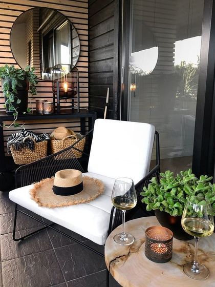 A chic and modern corner for one. This design uses a minimalist black and white palette, with a comfortable lounge chair, a stylish side table for a glass of wine, and simple greenery to create a sophisticated personal retreat.