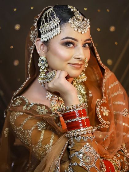 A smiling portrait of the bride, highlighting her beautiful red chooda and nath.