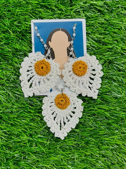 This handmade crochet jewelry set features a daisy-inspired design in white and yellow. The set includes a delicate necklace and matching earrings, perfect for a fresh and simple everyday style.
