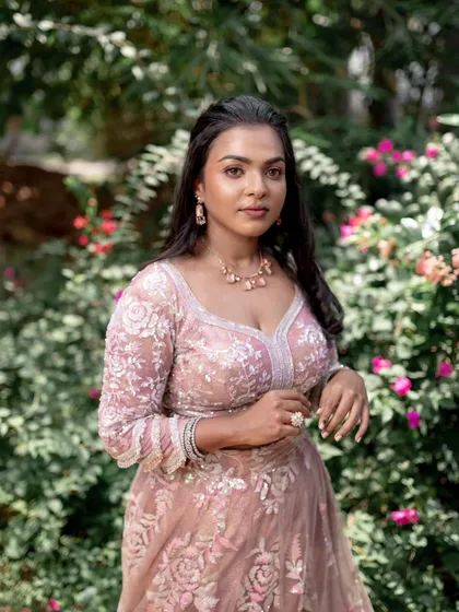 A model posing in a beautiful pink lehenga, showing off a subtle and elegant makeup look.