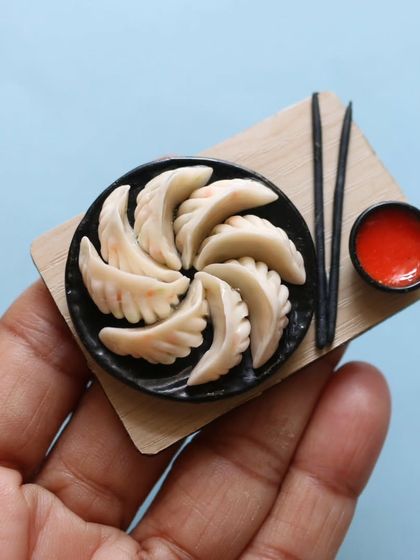 A handmade miniature of momos, complete with a dipping sauce and chopsticks.