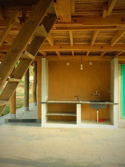 The outdoor kitchen area of the farm pavilion, with a simple stone counter and a brightly painted door adding a touch of color.