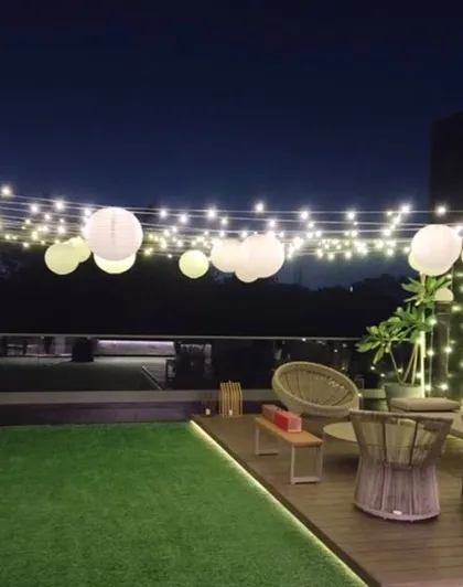 Another view of the terrace lighting setup, showing how the combination of string lights and paper lanterns can transform an outdoor space for a special occasion.