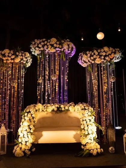 A glamorous Sangeet seating area with a backdrop of hanging crystals and disco balls. The stage is framed with white flowers, creating a chic and dramatic look perfect for a night of performances.