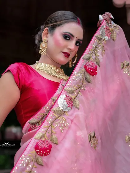 A close-up shot highlighting the floral embroidery on the border of the pink saree.