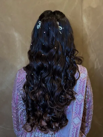 The hairstyle featured soft, open curls decorated with pretty, bow-shaped crystal clips and scattered pearls.