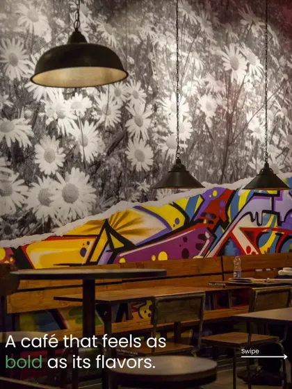To make a cafe feel as bold as its flavors, I blend different textures and art styles. This wall combines a classic floral wallpaper with a modern, colorful graffiti mural, creating a unique visual focal point that is both artistic and energetic.