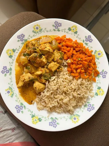 A healthy dinner of brown rice, chicken curry, and chopped carrots. I often keep my dinners simple and ensure they include a lean protein source and vegetables.