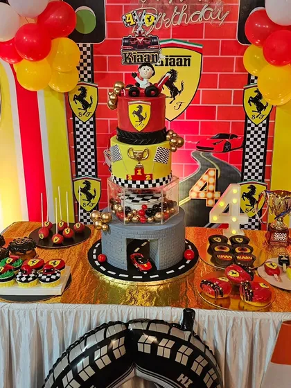 The full Ferrari-themed dessert table, featuring the main cake, cupcakes, donuts, cakesicles, and chocolate-covered Oreos.