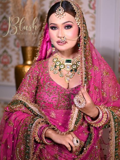 A full view of a stunning Muslim bride. The vibrant pink and green outfit is complemented by a bold eye makeup look, showcasing my ability to create looks that match the grandeur of the occasion.