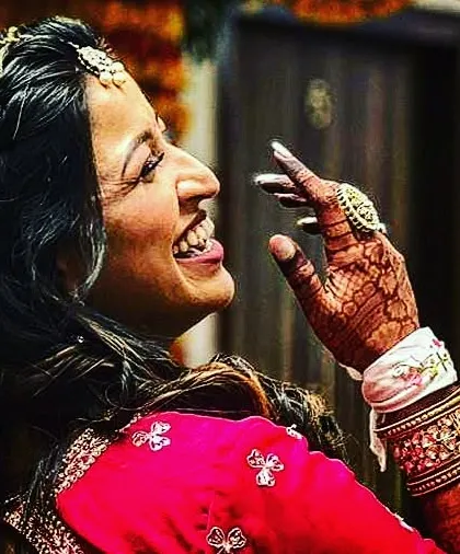 A smile is the best accessory for a bride. This candid photo captures a bride's pure happiness, with her detailed mehndi beautifully accenting her hand as she laughs.
