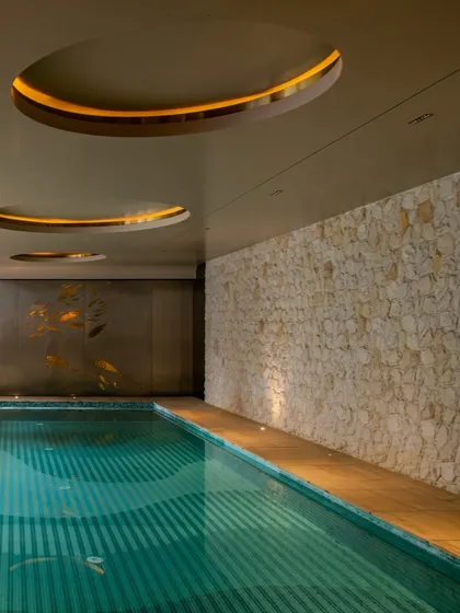 Another view of the Outhouse basement pool, showing the textured stone wall and circular ceiling cutouts with ambient lighting. Every detail is designed to create a sense of indulgence and escape.