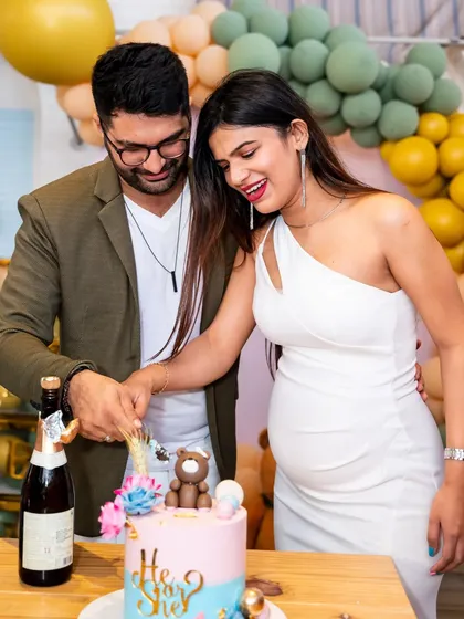 The happy couple-to-be cuts their "He or She?" gender reveal cake at their baby shower.