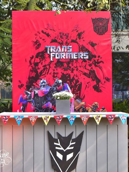 A themed counter with a dramatic red backdrop featuring Transformers characters. This area can be used for drinks, food, or as a station for party favours.