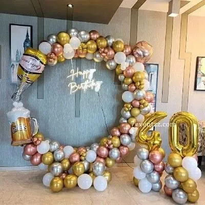 A fun and festive 40th birthday setup with a beer theme. The circular balloon arch in rose gold, gold, and silver features champagne bottle and beer mug foil balloons.