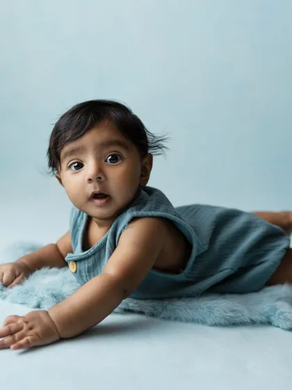 All that cuteness. A tummy-time shot on a soft blue background, perfect for showing off those baby rolls.