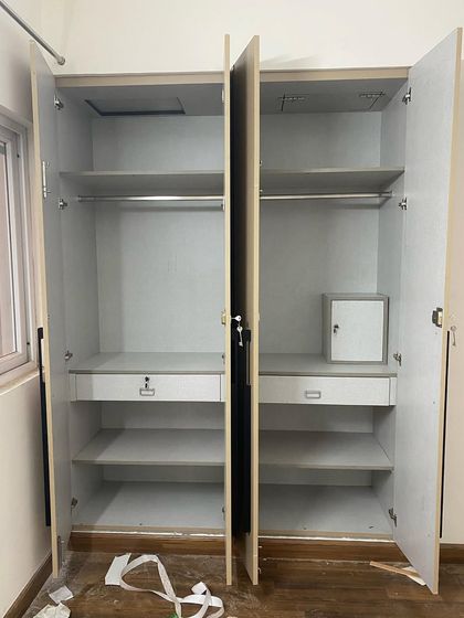 The internal view of a four-door wardrobe, showing a symmetrical layout with hanging space and drawers on both sides.