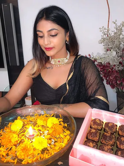 A quiet moment during the Diwali celebration. The focus is on the traditional jewelry and the simple beauty of the black saree.