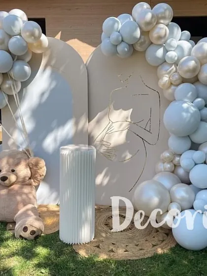 For a minimalist and modern aesthetic, I designed this all-white baby shower theme. The clean lines of the backdrops, one featuring a line-art drawing, are softened by fluffy white balloons and a classic teddy bear.