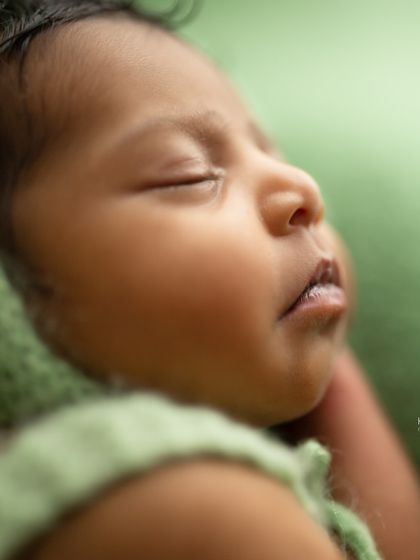 A black and white close-up of a newborn's face, highlighting their soft skin and peaceful sleep. The focus on texture and light creates a timeless piece of art.