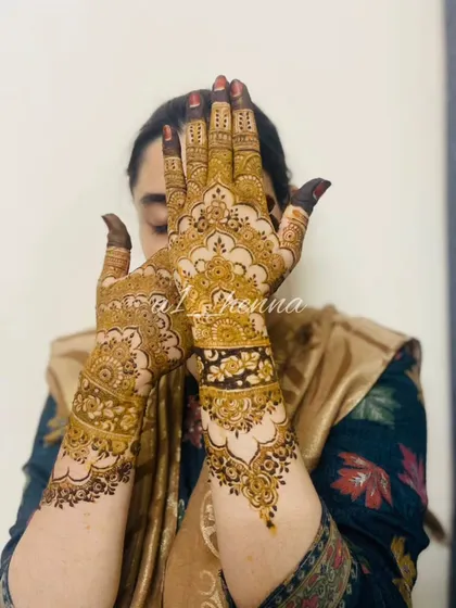 A graceful pose showing off a detailed Pakistani-style henna design. The patterns flow beautifully from the wrist to the fingers.