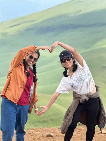 Two friends making a heart shape together, sharing their love for the mountains at Netravathi.