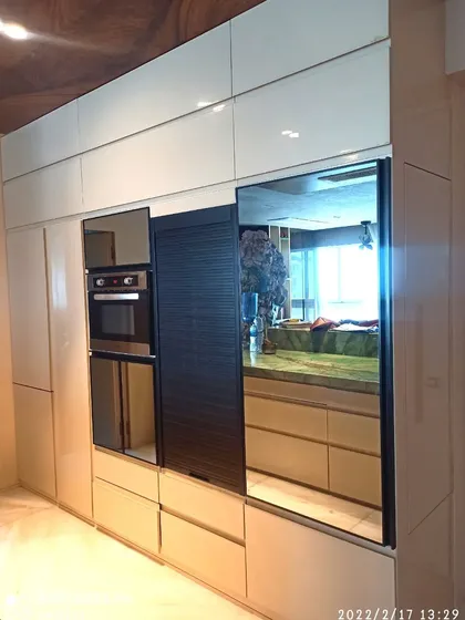 This is a section of a high-end kitchen I delivered, featuring high-gloss PU shutters and a black rolling shutter. I integrated the oven seamlessly and used a mirrored profile shutter to add depth and a modern look.