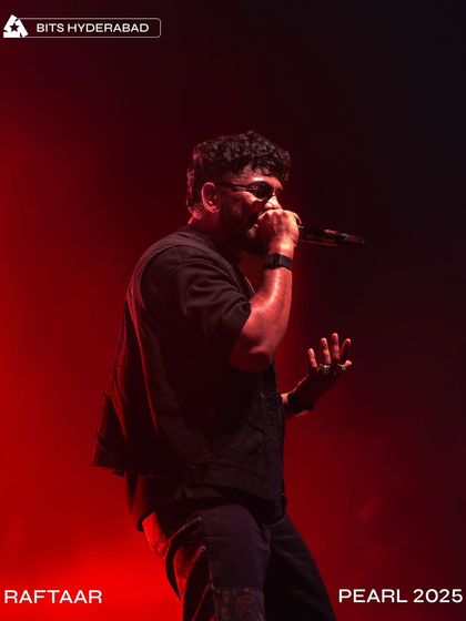 A dramatic, red-lit shot of Raftaar commanding the stage at Pearl 2025.