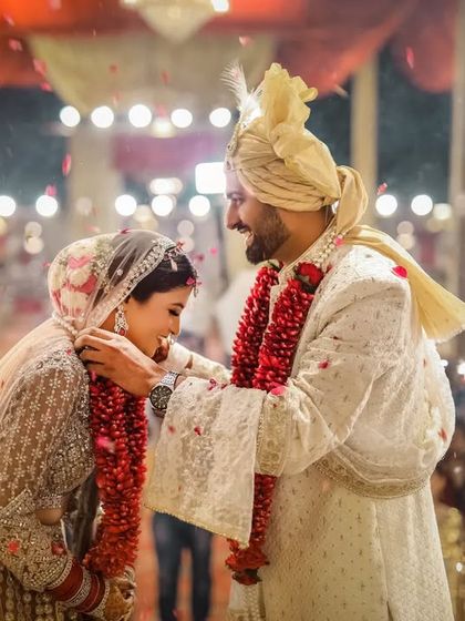 The groom places the varmala around the bride's neck, a key moment filled with smiles and the sparkle of pyrotechnics.