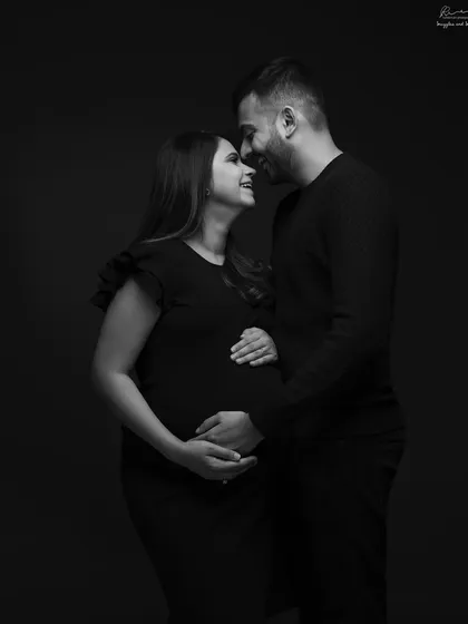 A classic and loving embrace. This black and white couple portrait, with both partners holding the bump, is a beautiful symbol of their shared journey.