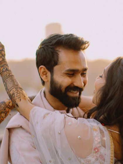 A golden hour portrait filled with warmth and laughter. The bride's arms around the groom create a beautiful, candid moment.