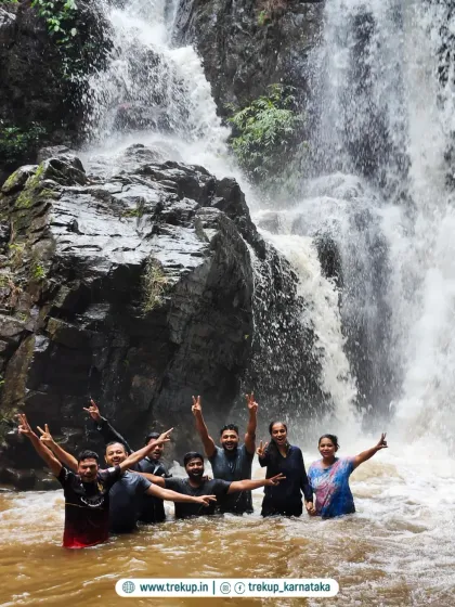 A group having the time of their lives, splashing around in a waterfall pool.
