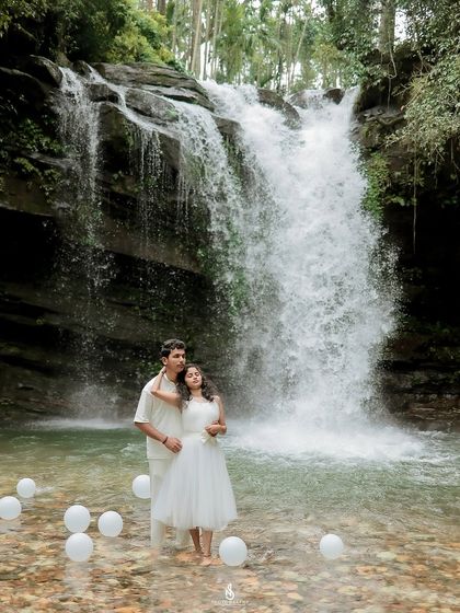 An embrace in the shallows of the waterfall pool. The all-white outfits create a striking contrast against the powerful cascade of water.