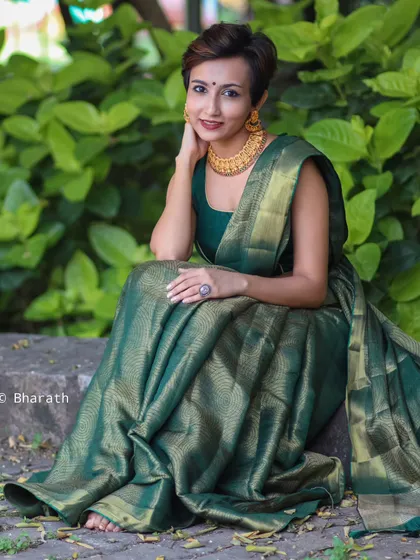 A seated portrait showcasing the beautiful drape of the green silk saree. The model's confident pose and modern hairstyle make this a perfect example of fusion fashion.