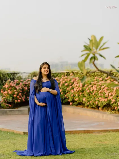 Standing tall and beautiful, this mama-to-be glows against a backdrop of soft pink flowers in a lovely Mumbai garden.