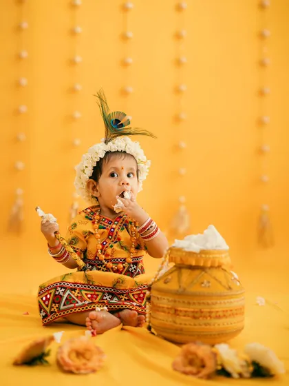 This adorable baby girl, dressed as Radha, gets a taste of the butter during her Janmashtami photoshoot. We capture these spontaneous, sweet moments.