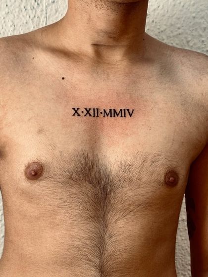 Another shot of the Roman numeral chest tattoo, showing the clean, crisp lines of the font.