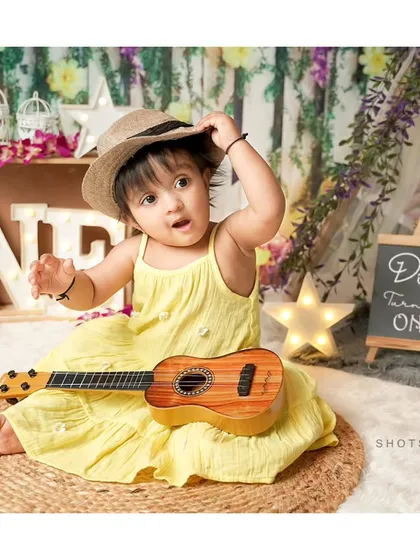 A little musician in the making. Using props like a ukulele and a hat adds a fun, playful element to this first birthday shoot.