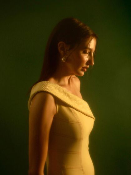 A soft, moody shot of a model in a yellow off-shoulder dress. The lighting creates a gentle, painterly effect that adds a touch of romance to the image.