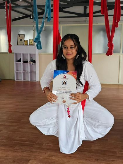 A newly certified aerial yogi, celebrating her achievement after completing our specialized TTC.