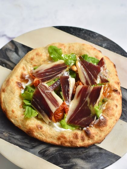 The Jamon Ibérico Flatbread from our Spanish pop-up. We top our freshly baked sourdough flatbread with creamy mascarpone, arugula, and high-quality Spanish ham.