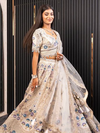 A full-length shot of the ivory and silver lehenga, showing its beautiful flare and intricate floral embroidery. This is a perfect rental for the modern bride who loves classic elegance.