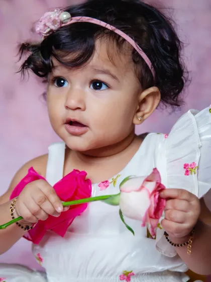 A sweet studio portrait of a baby girl holding a rose. Props can add a lovely touch of color and interest, and her curious expression here is just priceless.