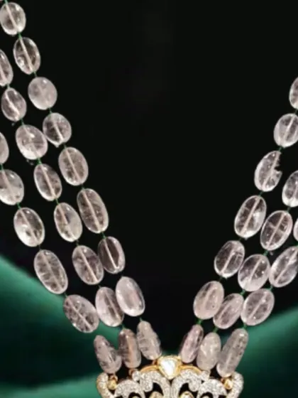 This royal necklace features strings of morganite beads leading to an intricate pendant. The design incorporates elephant motifs, polki, diamonds, and a touch of emerald for a truly unique heritage piece.