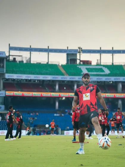A wide shot of me on the field at a large stadium, juggling a football. Even during warm-ups, the focus is on skill and control.