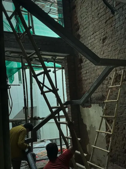 A custom metal staircase being installed against an exposed brick wall. This feature will become a modern, industrial-style focal point in the space.